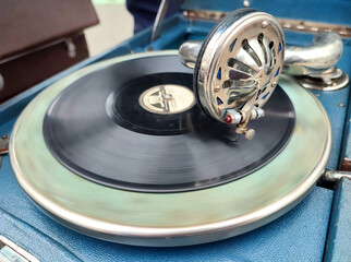 An old retro record playing on old vintage gramophone at flea market. Work of portable gramophone....
