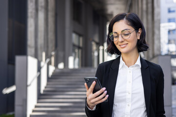 Confident professional businesswoman using smartphone in urban environment