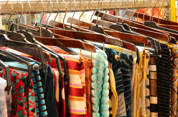 fabrics on hangers neatly arranged in a shop selling clothes and fine fabrics of haute couture...