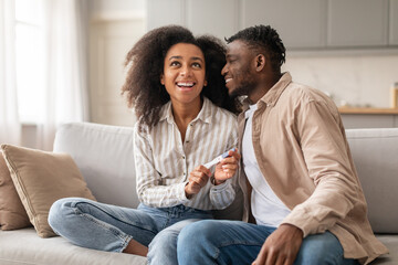 black millennial couple celebrating positive pregnancy test result at home