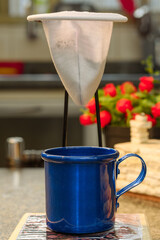 Cup of coffee under a cloth coffee strainer, individual portion.
