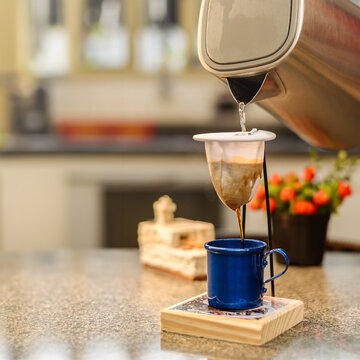 Pouring hot water into a cloth coffee strainer. Making an individual portion of black coffee.