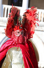 Masked woman with yellow wig and her friend during the Venice Carnival in Italy