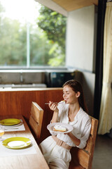 Smiling Woman Enjoying Romantic Dinner at Home A beautiful brunette woman is sitting at a trendy,...