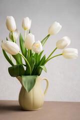 A bouquet of white tulips in a yellow jug