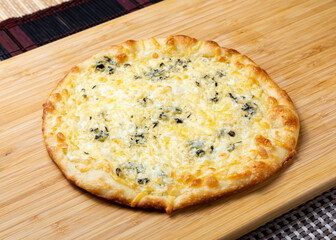 Four cheese pizza on a wooden board.