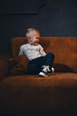 Adorable Handsome Little Cute Boy on Vintage Sofa in Dark Interior - 746081940