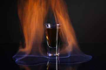 Flaming alcohol drink in shot glass on dark background