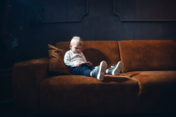 Handsome Little Rich Boy with Smartphone Sitting in Dark Interior - 746082189