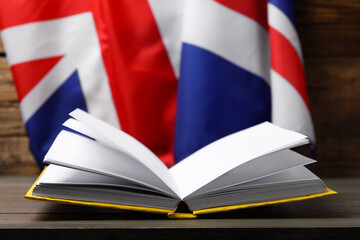 Learning foreign language. Open book on wooden table flag of United Kingdom, space for text