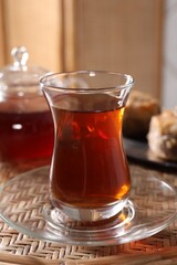 Traditional Turkish tea in glass on wicker table, closeup