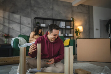 young couple moving in new apartment carry assembly furniture