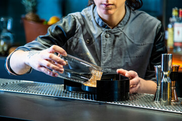 Camarera de cocktail bar prepara bloody Mary sobre una barra de un cocktail bar exclusivo en ambiente nocturno con detalle sobre el cocktail exquisito