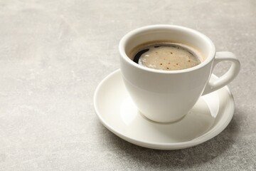 Cup of aromatic coffee on light grey table, closeup. Space for text