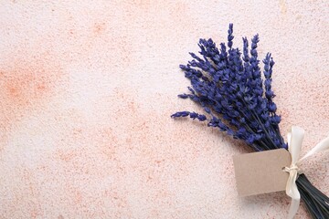 Bouquet of beautiful preserved lavender flowers with blank tag and ribbon on color textured table,...