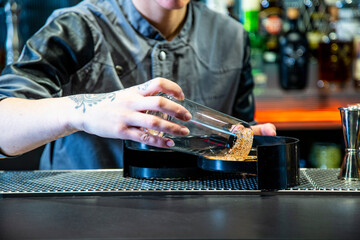 Camarera de cocktail bar prepara bloody Mary sobre una barra de un cocktail bar exclusivo en ambiente nocturno con detalle sobre el cocktail exquisito