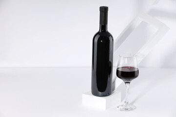 Stylish presentation of delicious red wine in bottle and glass on white background. Space for text