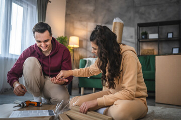 young couple moving in new apartment carry assembly furniture