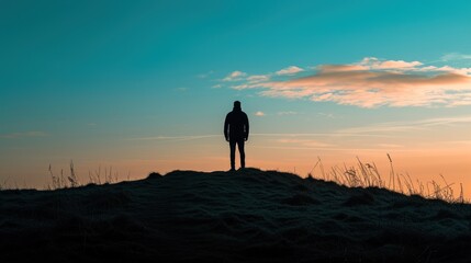 a person standing on top of a hill with the sun setting in the sky behind them and grass in the foreground.