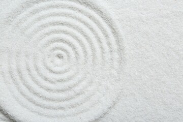 Fototapeta na wymiar Zen rock garden. Circle pattern on white sand, top view. Space for text