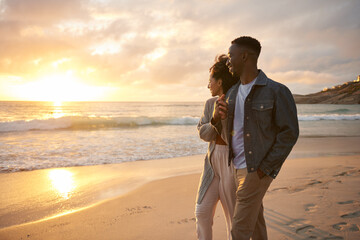 Smiling young multiethnic couple watching the sunset on a beach