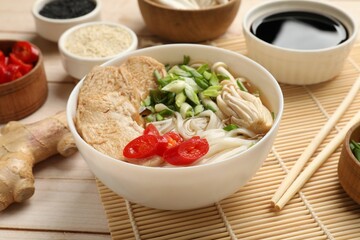 Delicious ramen with meat and ingredients on white wooden table, closeup. Noodle soup