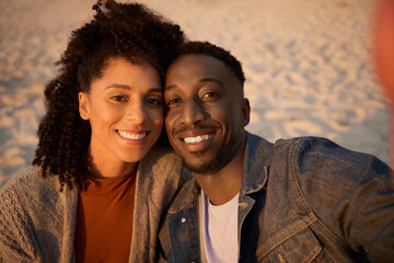 Smiling young multiethnic couple taking a selfie on a sandy beach