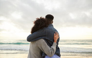 Loving multiethnic couple looking out at the ocean from a beach