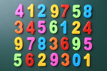 Colorful numbers on green background, flat lay