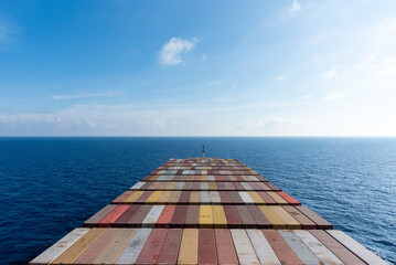 Aerial view on the containers loaded on deck of the large cargo ship. She is sailing through calm,...