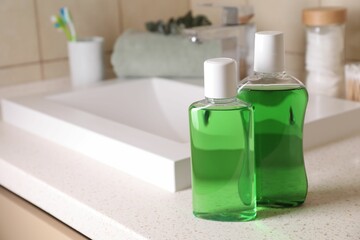 Fresh mouthwashes in bottles on countertop in bathroom, closeup. Space for text