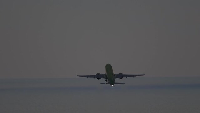 Airplane silhouette in the evening cloudy sunset sky, rear view. Footage of aircraft departure. Plane take off.