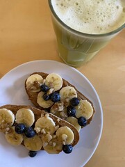 American breakfast with toast, banana, blueberries, maple syrup, nuts and green smoothie