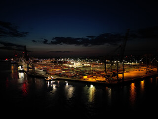 Naklejka na ściany i meble Aerial panoramic view of illuminated Southampton container terminal at dusk. Lights reflection on the sea.