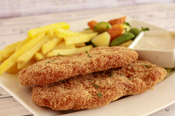 CHICKEN ESCALOPE with French Fries, Salad and Dip served in dish isolated on table side view of arabic fastfood