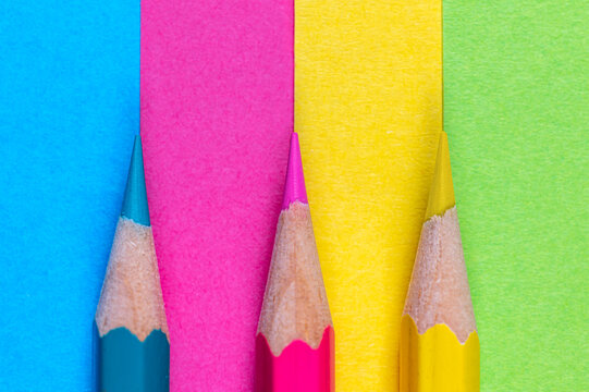 Drei Buntstifte mit passendem farbigen Papier als Hintergrund oder Textur