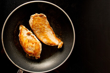 Fried chicken inside a black skillet pan in top aerial view