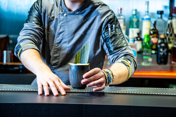 Barman prepara cocktail de piña colada sobre la barra de un cocktail bar nocturno close up con detalles exclusivos