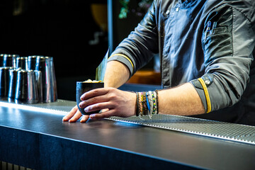 Barman prepara cocktail de piña colada sobre la barra de un cocktail bar nocturno close up con detalles exclusivos