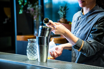 barman prepara un cocktail de piña colada con hoja de piña en un vaso decorado sobre la barra de un cocktail bar exclusivo por la noche en ambiente de fiesta, camarera close up