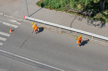 Municipal cleaners manually sweep the city roadway
