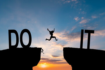 Silhouette man jumping over I can do it wording on cliffs with cloud sky and sunrise. Never give...