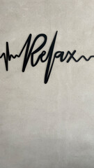 Palabra RELAX con tipografía electrocardiograma sobre pared de cemento con textura, toma vertical