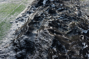 Artificial turf infill mixed with snow and ice by a football field.