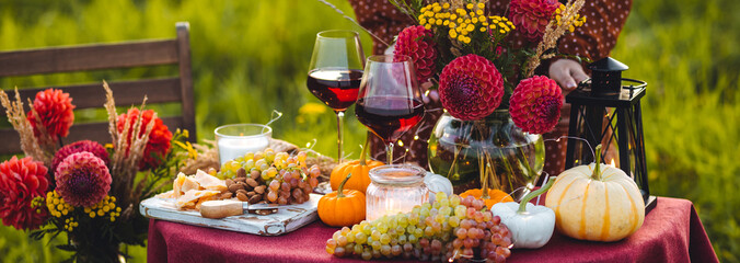 Beautiful elegant fall wedding table setting or thanksgiving dinner decor or romantic lunch outdoors. Pumpkins, fresh flowers, delicious food, red wine. Cozy autumn atmosphere, countryside vibe banner