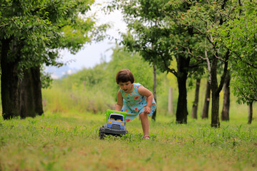 Fototapeta premium Happy little girl playing under fruit trees