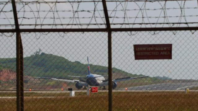 Widebody airliner braking after landing at Phuket airport, rear view. Spoilers up