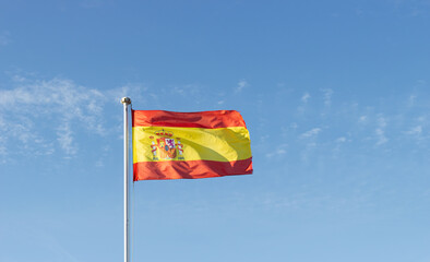 Spain's national flag fluttering in a clear blue sky.