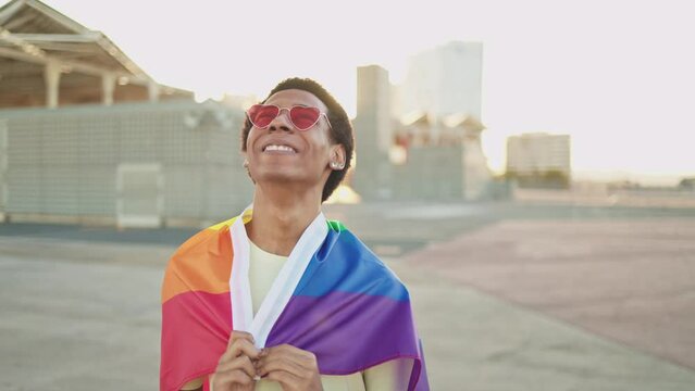 African American gay man with rainbow LGBT flag at Pride parade. Lesbian, gay, bisexual, transgender social movements. Concept of happiness freedom love same-sex couple. LGBTQ