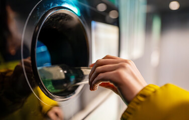 Woman puts bottle in automatic bottle recycling machine. Reverse vending recycling machine. - obrazy, fototapety, plakaty
